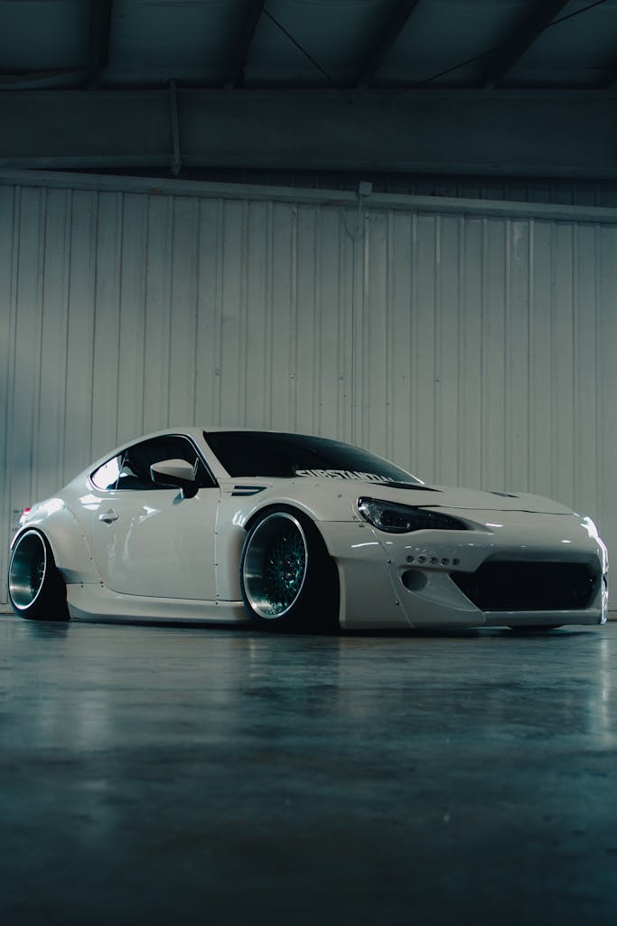 White Toyota GT86 with aftermarket widebody kit in an indoor garage setting.