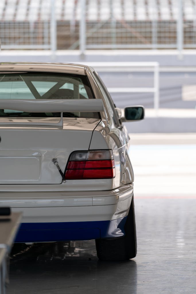 Close-up of a white racing car in a garage, capturing sleek design and sportiness.