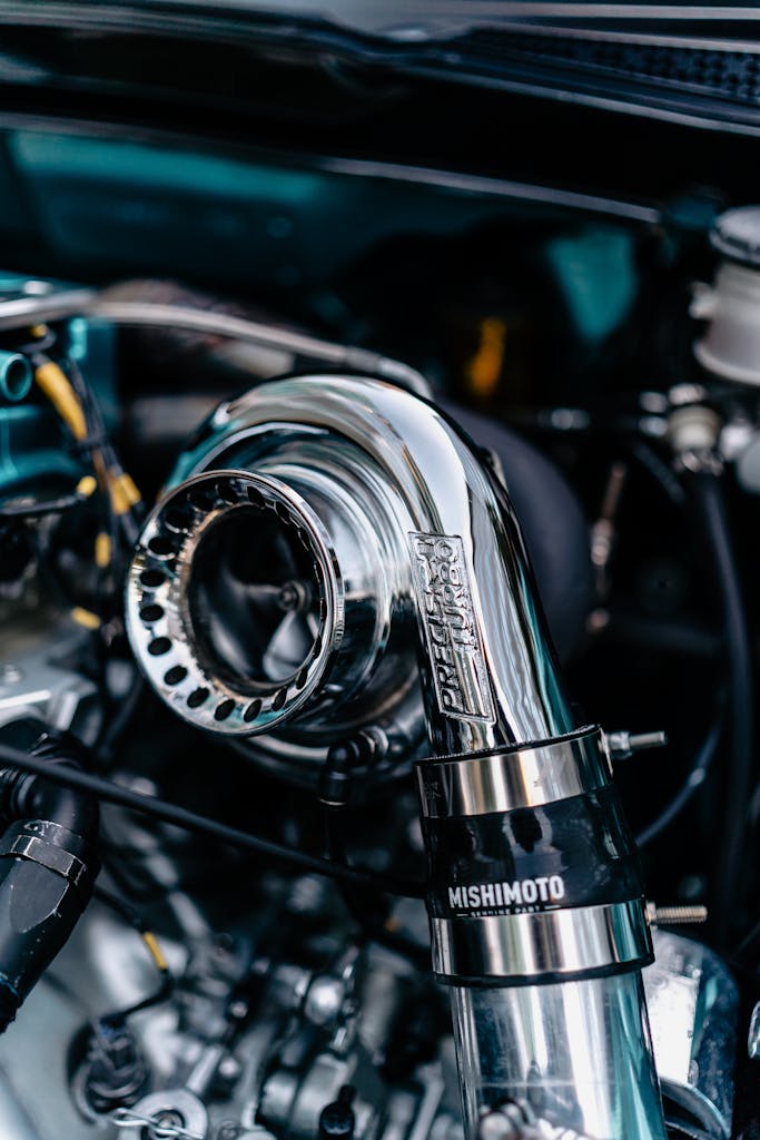Detailed shot of a chrome turbocharger in a car engine bay, reflecting light.