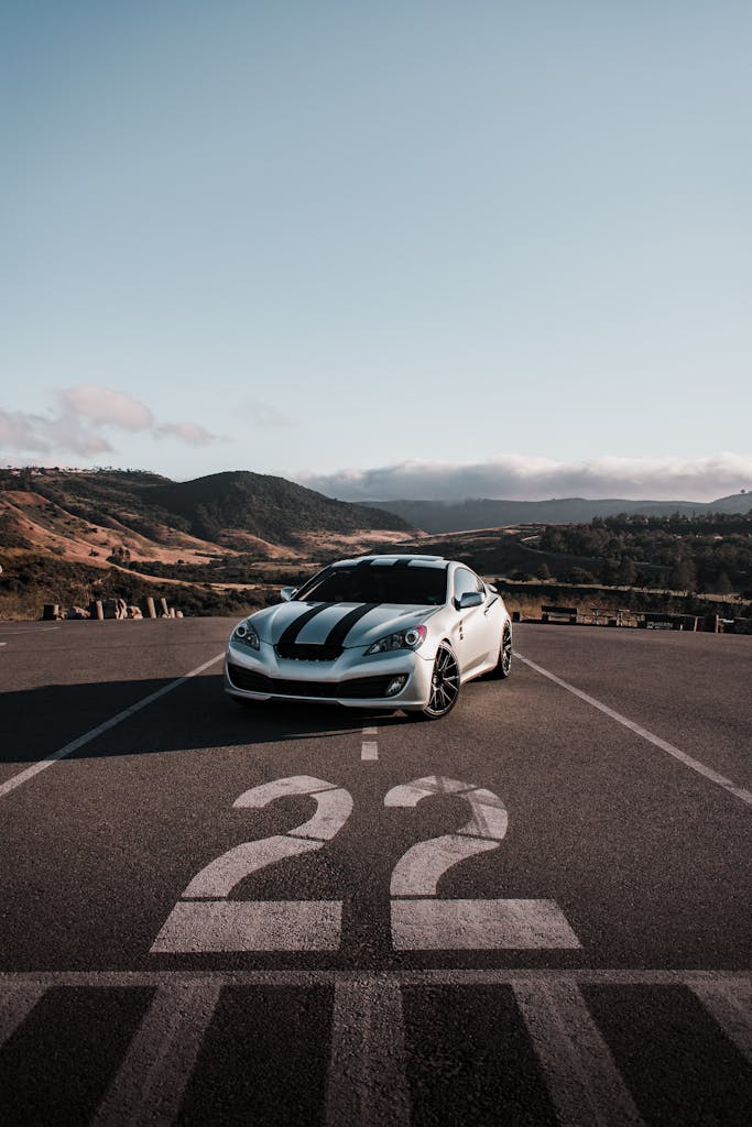 Dynamic sports car parked on racing track with number 22, featuring scenic mountain backdrop.