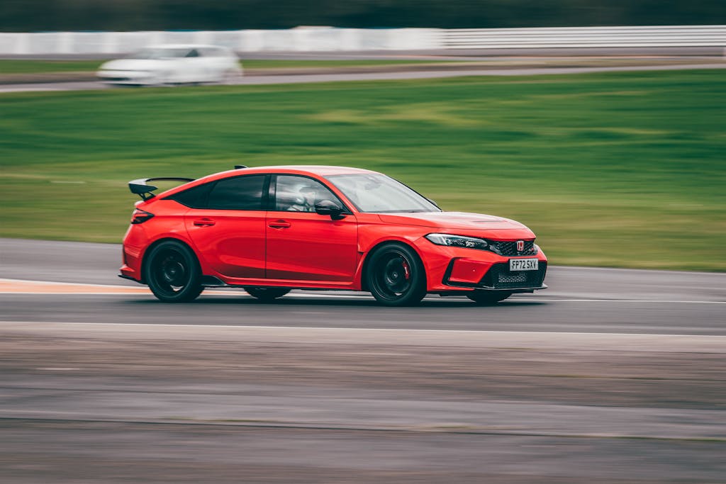 Red Honda Civic Type R speeding on Blyton Park racetrack in England.